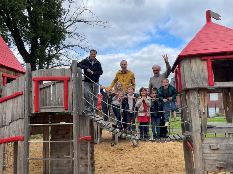 Eine Gruppe Menschen steht auf einer Hängebrücke auf dem Spielplatz.